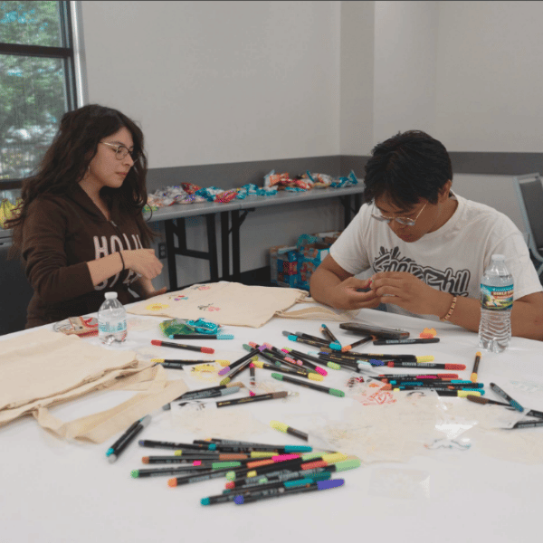 two students coloring at a table in front of sweet snacks at table